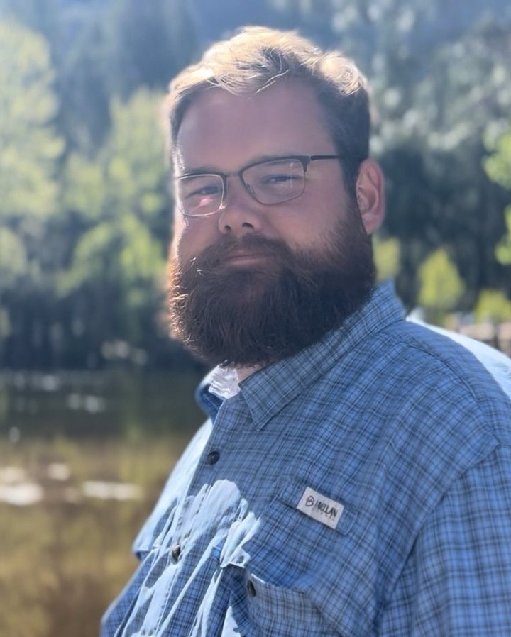 Trent Haire standing beside a river in the woods